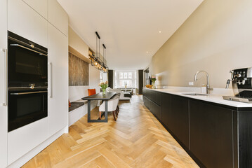 a modern kitchen with wood flooring and an oven on the wall in the center of the space is white