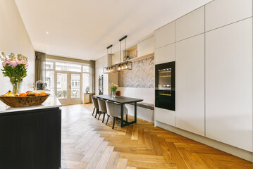 a modern kitchen with wood flooring and white cabinets in the center of the room is a bowl of fruit