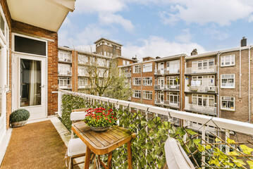 a balcony with flowers on the table and some buildings in the background, taken from an apartment's...