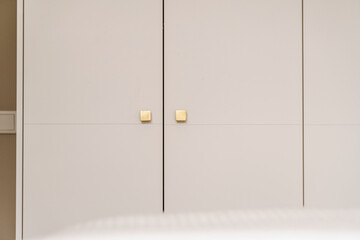 two white cupboards with gold handles and knobs in a room that has no one on the cabinet door