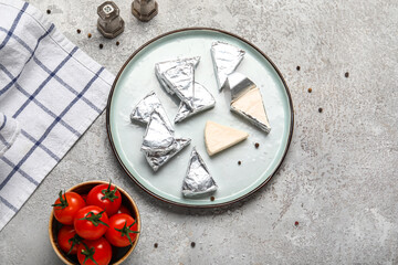 Fototapeta na wymiar Plate with triangles of tasty processed cheese and tomatoes on grey background