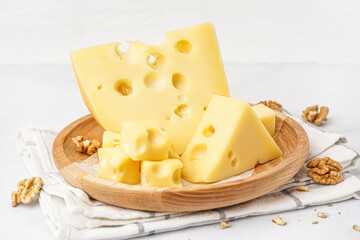 Plate with pieces of Swiss cheese and walnut on white background