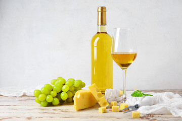 Tasty Swiss cheese, grapes, bottle and glass of wine on table