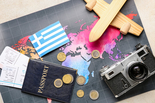 World map, flag of Greece, wooden plane, euro coins and passport on beige table. Traveling concept