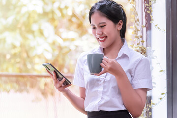 Asian businesswoman holding a cup of coffee relaxing in the office.