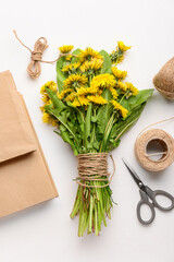 Bouquet of beautiful dandelion flowers, rope, scissors and books on light background, closeup