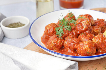 Bowl of tasty meat balls with tomato sauce and dill, closeup