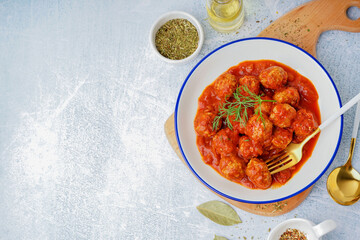 Bowl of tasty meat balls with tomato sauce and dill on blue background
