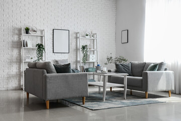 Interior of light living room with cozy grey sofas and coffee table