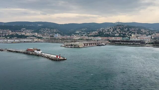 The skyline of Trieste in Italy. Wind makes waves in the sea and there is a lot of traffic in the city. Time lapse