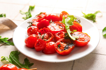 Plate with tasty grilled tomatoes and arugula on white tile background