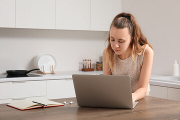 Female freelancer working with laptop at table in kitchen