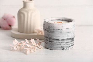Holder with candle and reed diffuser on white wooden background