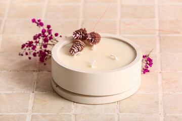 Fototapeta na wymiar Holder with candle and flowers on beige tile background