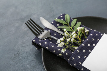 Beautiful table setting with clean plate, cutlery and gypsophila flowers on black table