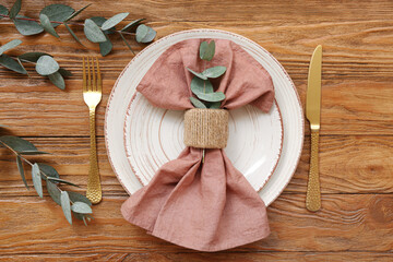 Fototapeta na wymiar Beautiful table setting with eucalyptus branches and folded napkin on wooden table