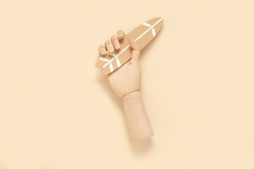 Wooden hand with mini surfboard on beige background