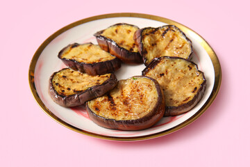 Plate with delicious grilled eggplants on pink background