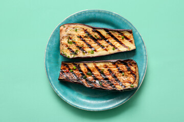 Plate with delicious grilled eggplants on turquoise background, top view