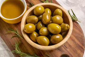 Bowls with ripe olives and oil on light background