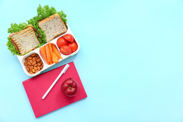Fototapeta na wymiar Stationery and lunch box with tasty food on blue background