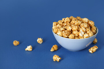Bowl with tasty popcorn on blue background