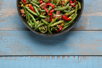 Frying pan with different vegetables on blue wooden background