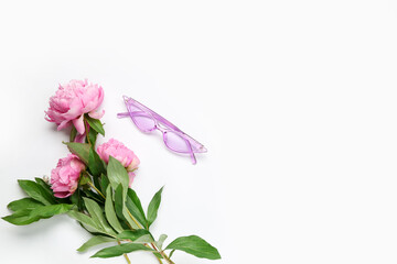 Stylish female sunglasses and beautiful peony flowers on white background