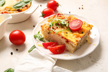 Baking dish and plate of pasta with tomato sauce on white background