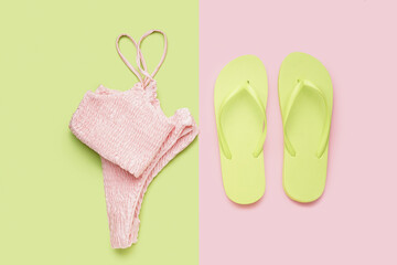 Green flip-flops with pink swimsuit on color background