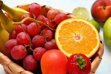 Wicker basket with different fresh fruits on light blue background