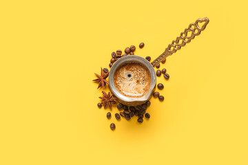 Cezve with coffee, beans and star anise on yellow background