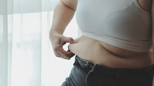 .Woman body fat belly. Obese woman hands holding excessive tummy fat. Change diet lifestyle concept to shape up healthy stomach muscle. Studio anonymous shot photo of body parts.