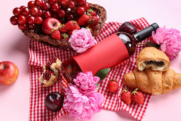 Composition with tasty food for picnic, bottle of wine and peony flowers on pink background, closeup