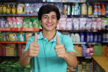 Happy Indian boy shopping in hypermarket buying grocery showing thumbs up