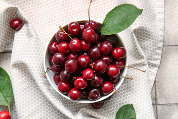 Bowl with sweet cherries on grey tile table