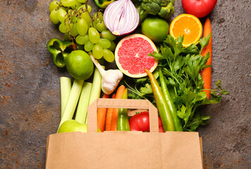 Paper bag with different fresh fruits and vegetables on dark background