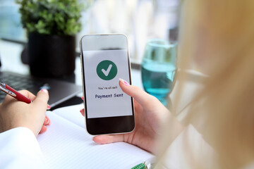 Woman using online banking on mobile phone. Payment sent.