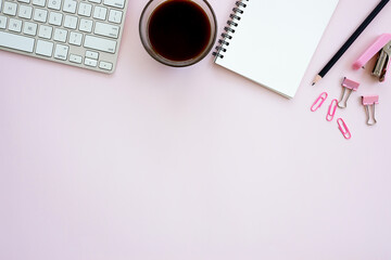Women office desk table with Table calendar, keyboard, laptops, notebook and coffee cup with equipment other office supplies on pink background. Flat lay with blank copy space.