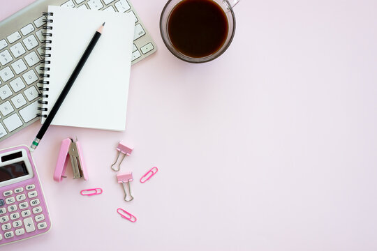 Women office desk table with Table calendar, keyboard, laptops, notebook and coffee cup with equipment other office supplies on pink background. Flat lay with blank copy space.