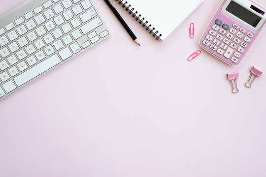 Women office desk table with Table calendar, keyboard, laptops, notebook and coffee cup with equipment other office supplies on pink background. Flat lay with blank copy space.
