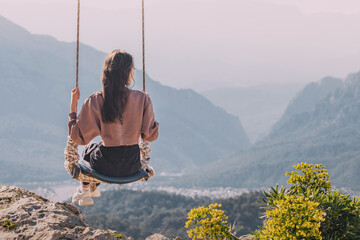 a woman on a swing overlooking the mountains and the sea near Kemer in Turkey