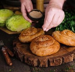 woman sprinkles seeds fresh twisted bun with sesame seeds