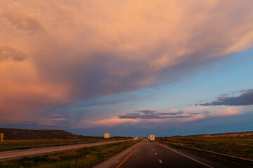 Fototapeta na wymiar Scenic landscape with highway among mountains and colorful sky at dusk. Blue, orange and purple sky at sunset over the road. Highway 40, Arizona, USA - 06-17-2022