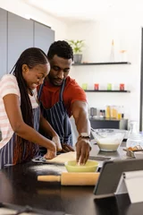 Keuken spatwand met foto Happy african american couple in aprons preparing bread dough in kitchen © WavebreakMediaMicro