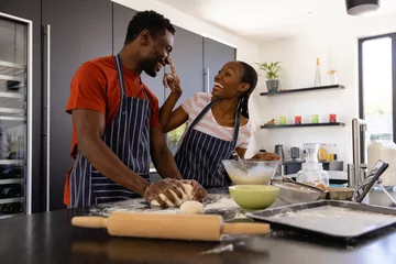 Foto op Plexiglas Happy african american couple in aprons preparing bread dough in kitchen © wavebreak3
