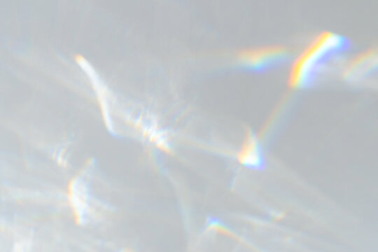 Blurred dreamy surreal rainbow crystal light refraction texture overlay. Prism Light Overlay Flare Background Organic drop holographic flare on a white wall. Water shadows for natural light effects