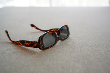 Fototapeta na wymiar Vintage rectangle brown sunglasses on sofa at hotel room in holidays