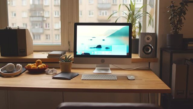 No people zoom in shot of computer with aesthetic nature desktop wallpaper on wooden table by window in warm cozy apartment
