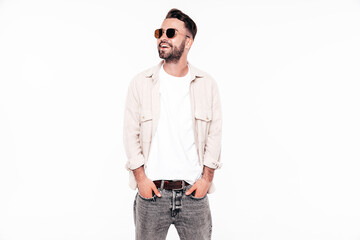Fototapeta premium Portrait of handsome smiling stylish hipster lambersexual model. Sexy man dressed in white T-shirt and jeans. Fashion male isolated on white background in studio. In sunglasses